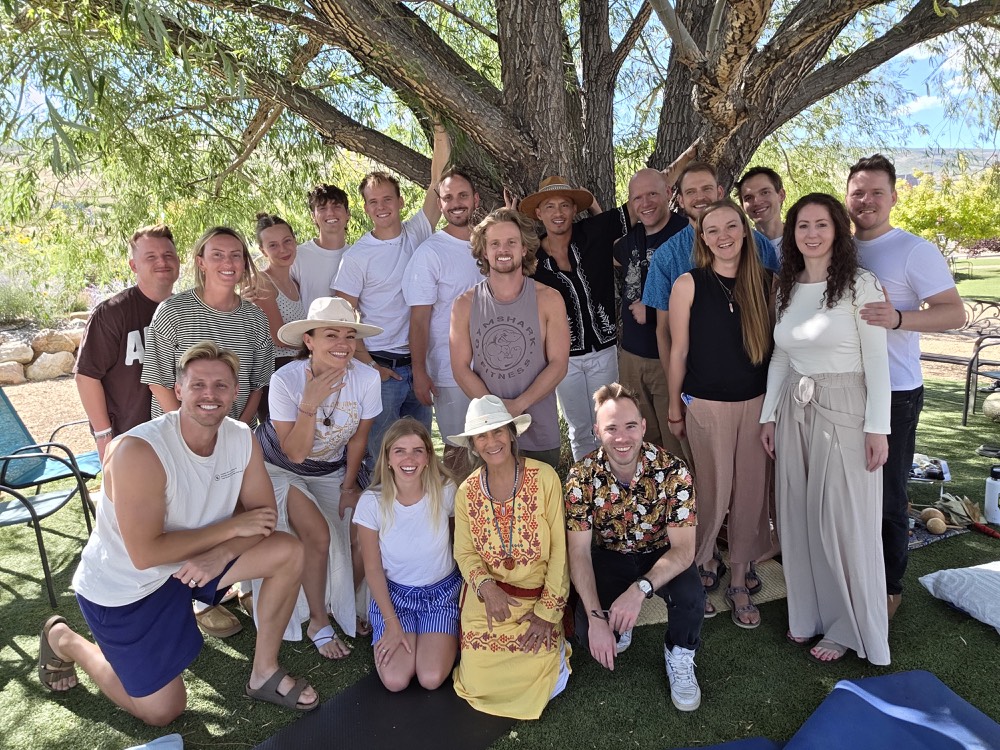 The circle gathered together under a willow tree, Mama Natema seated at the front in yellow