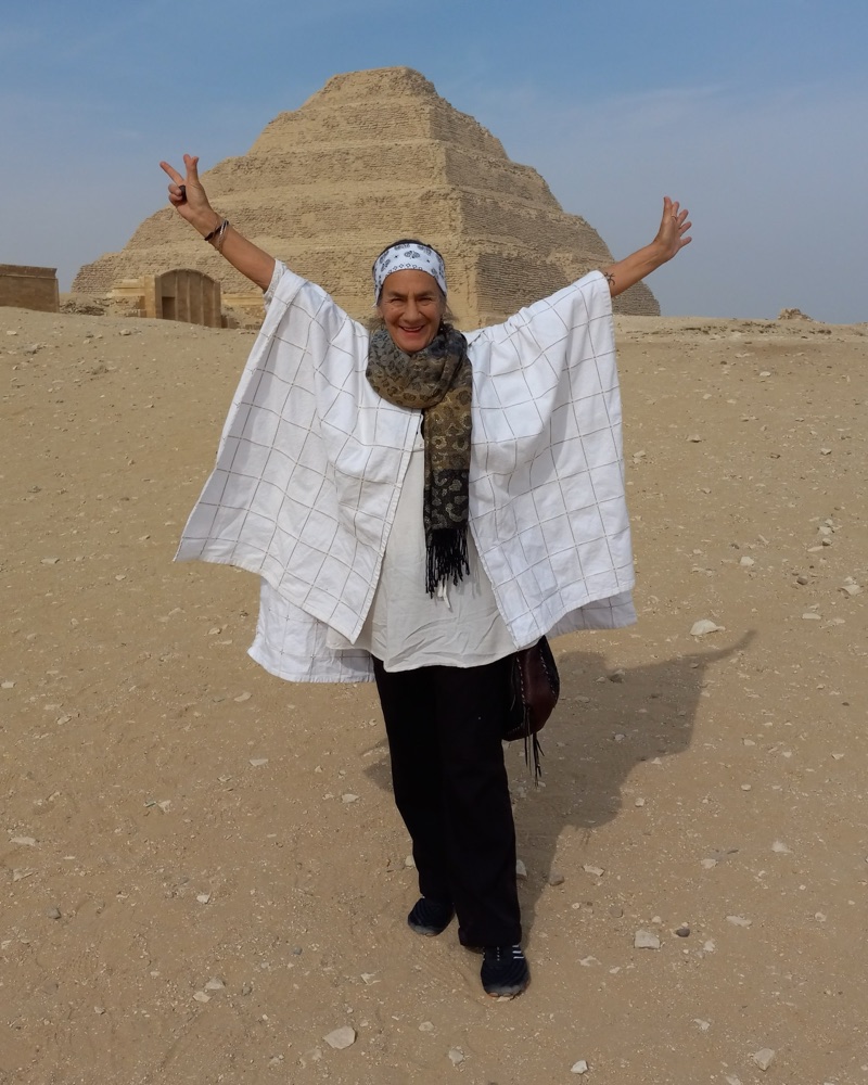 Mama Natema, arms raised before the step pyramid at Saqqara